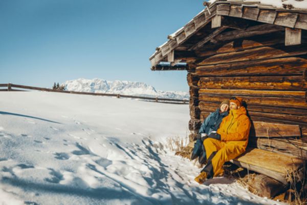 2 Winterurlauber vor einer Hütte im Schnee