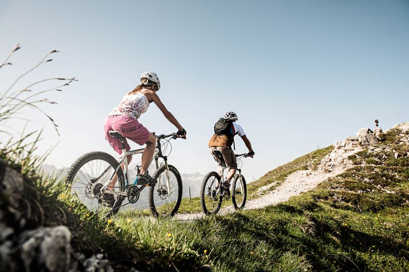 Eine Radfahrerin und ein Radfahrer im Sommer in den Bergen